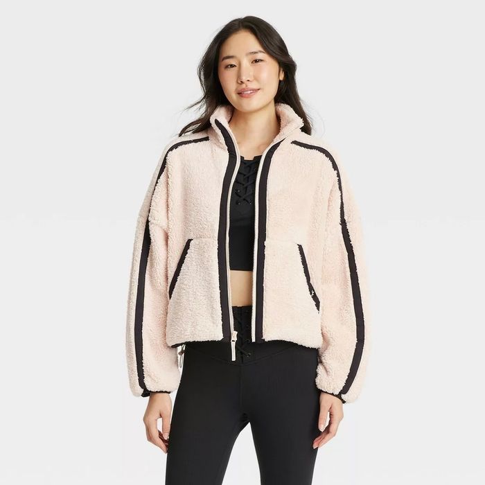 Model wearing a comfy, zip-up fleece jacket with black detailing.