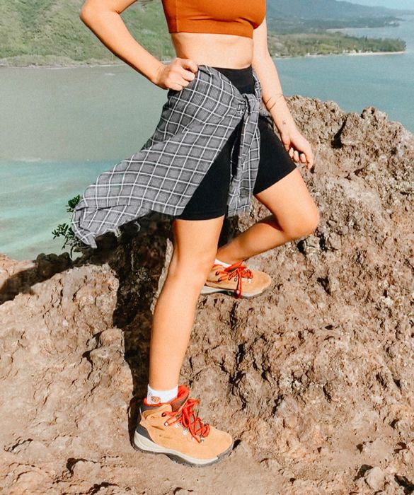 A reviewer outdoors sporting tan hiking boots with vibrant red laces