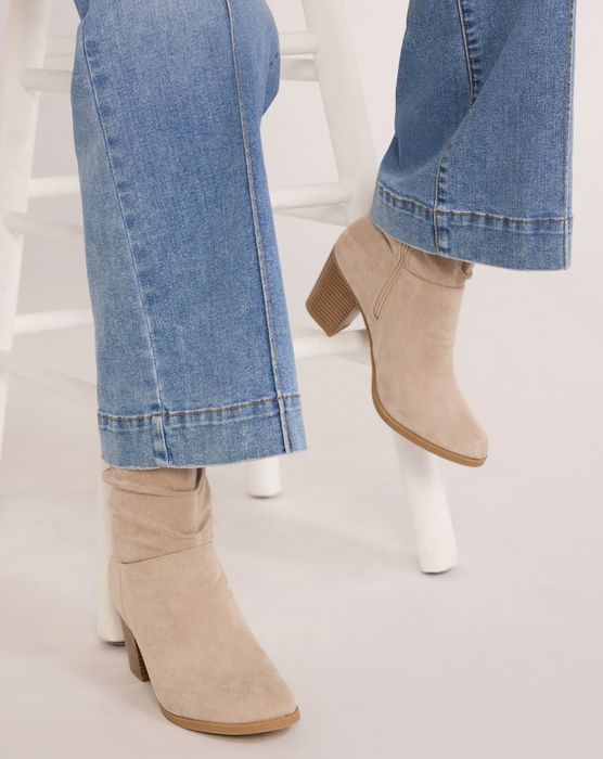 Ankle boots with block heels paired with rolled-up denim jeans, displayed against a white backdrop
