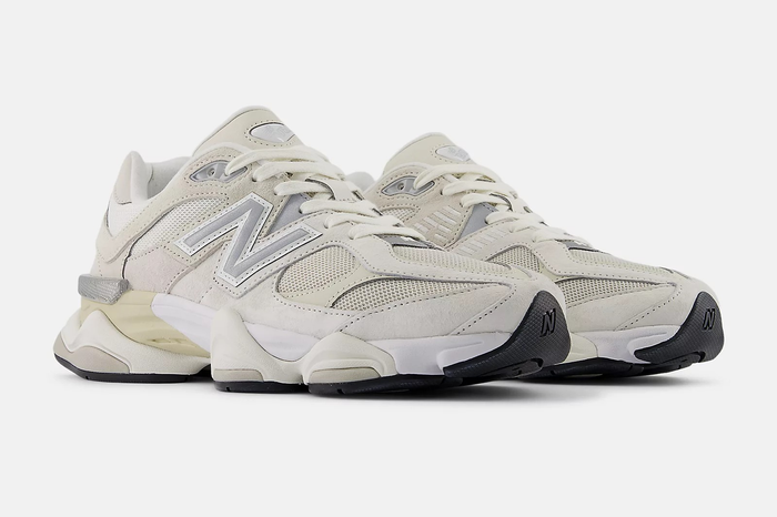 A pair of white New Balance sneakers with chunky soles, showcased against a simple backdrop
