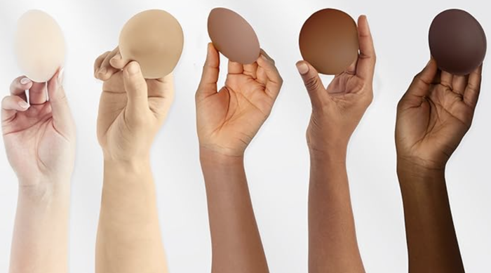 Five hands displaying foundation makeup samples in various skin tones, highlighting the diversity of cosmetic products