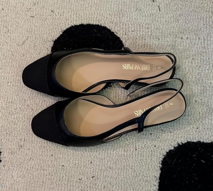 Two black slingback flats with square toes on a textured surface