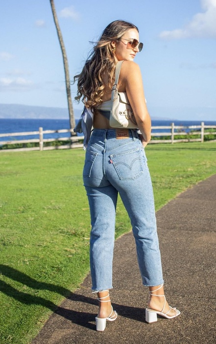 A reviewer striking a pose in the jeans paired with heels.