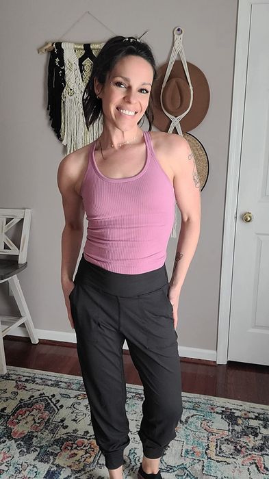 A reviewer wearing black joggers and a pink tank top.