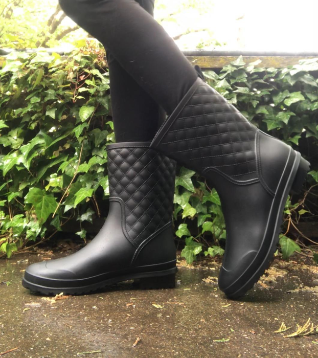 A reviewer wearing the rain boots