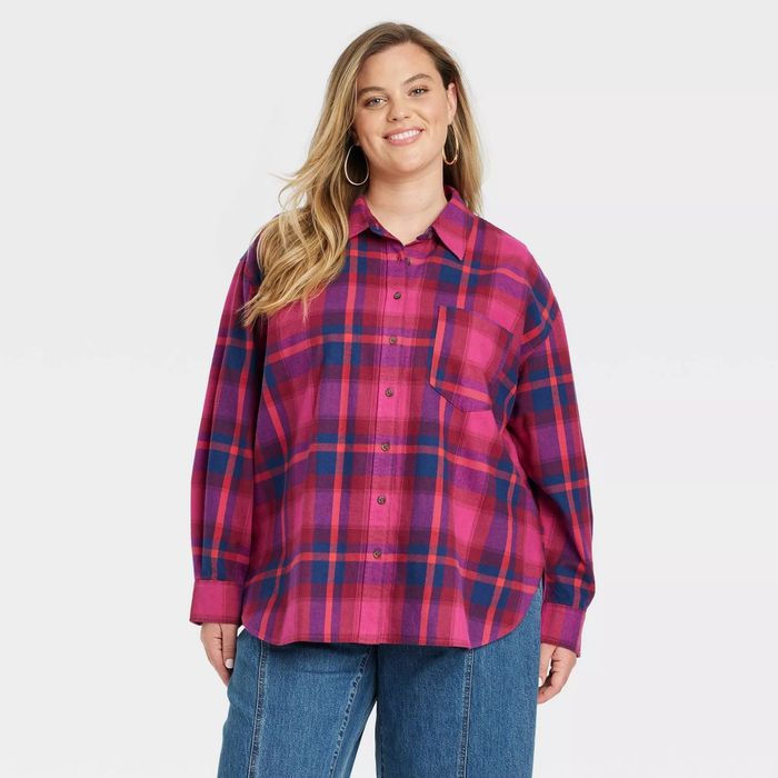 A model wearing a long-sleeve plaid button-down shirt styled with blue jeans, striking a pose during a fashion shoot
