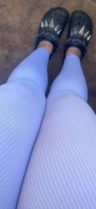 An individual sporting ribbed leggings paired with spiked Croc-inspired footwear