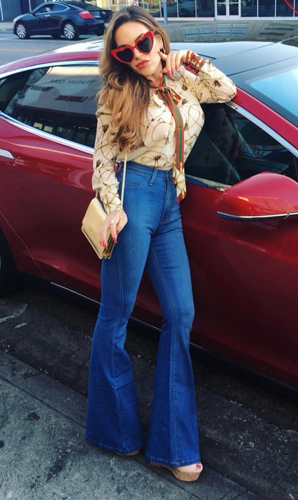 A reviewer strikes a pose in a pair of lighter wash bell-bottom jeans, adding a touch of retro flair.