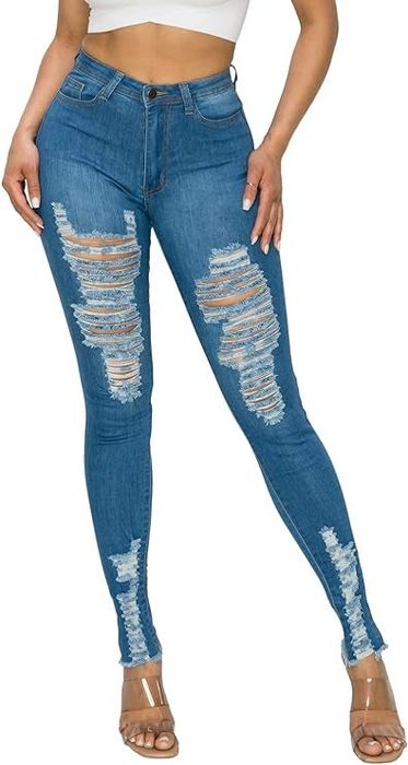 A model dons high-waisted distressed blue jeans with significant rips and tears at the thighs and knees, giving them a rugged, edgy look.