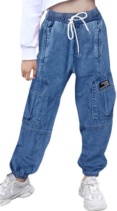A person showcasing denim jogger pants with elastic cuffs, large side pockets, and a drawstring waist, paired with white sneakers for a sporty yet stylish look.