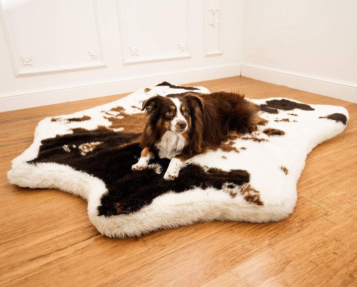 A dog resting on a cowhide-inspired orthopedic bed.