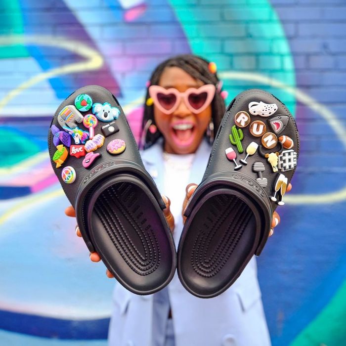A model holding up black Crocs adorned with charms