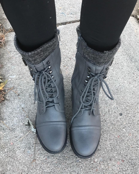 A reviewer wearing gray lace-up boots with black leggings tucked in