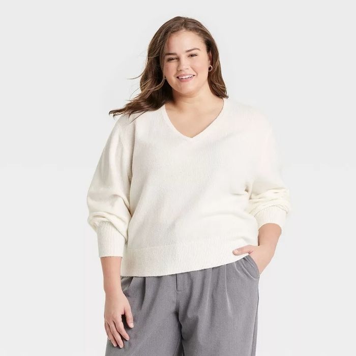 Model dressed in a V-neck sweater and relaxed trousers.