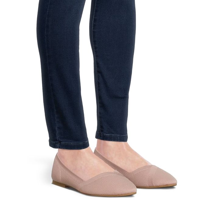 A woman dressed in navy blue jeans paired with stylish beige flat shoes
