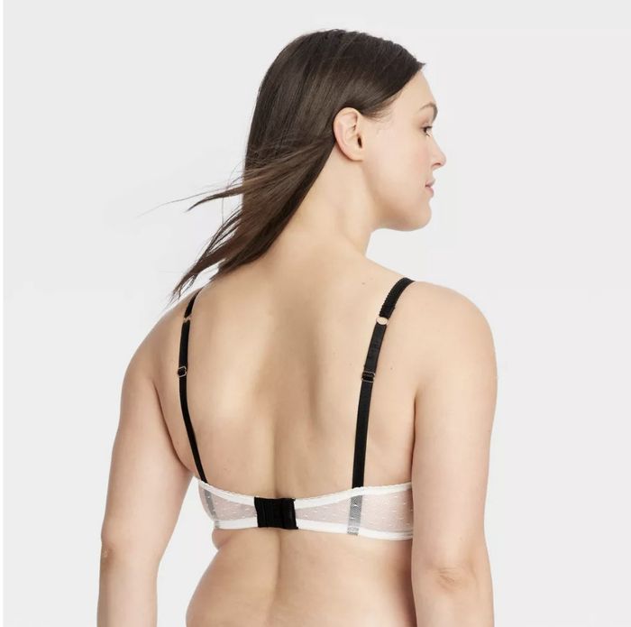 A model wearing a black and white bra featuring adjustable straps, viewed from the back