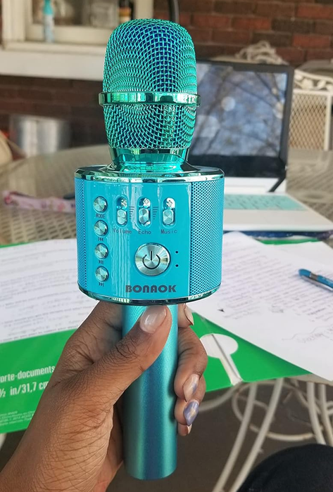 Reviewer holding a blue karaoke microphone with buttons