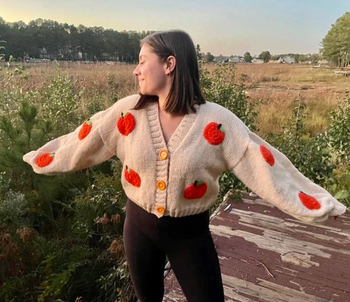 A model posing in the cardigan with arms outstretched