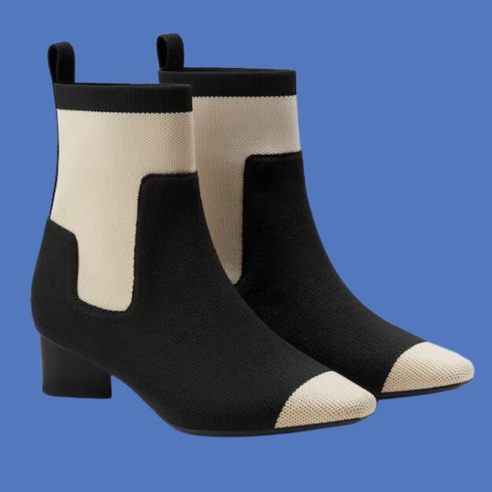 A pair of fashionable ankle boots featuring a sleek design with contrasting black and beige panels, thick heels, and convenient pull tabs.