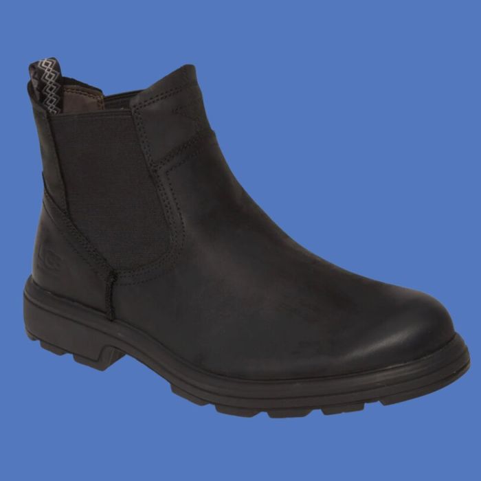 A black, ankle-high Chelsea boot with elastic side panels and a sturdy rubber sole. The boot is designed with subtle stitching details and a sleek, minimalist aesthetic.