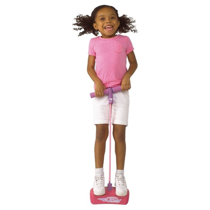 A child happily bounces on a pogo jumper indoors, wearing a t-shirt and shorts, featured in a shopping article