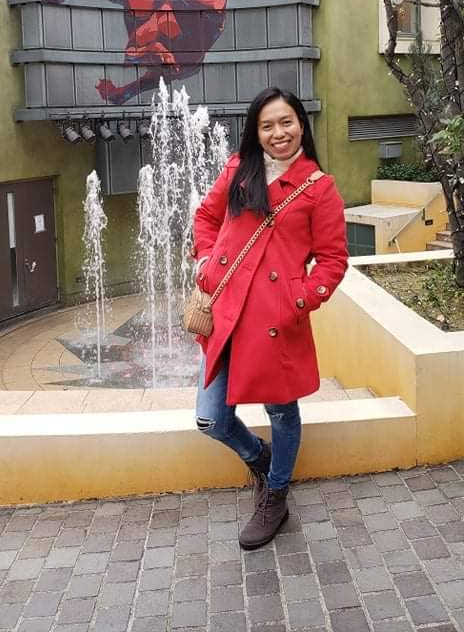 another reviewer wearing the red peacoat in front of a fountain