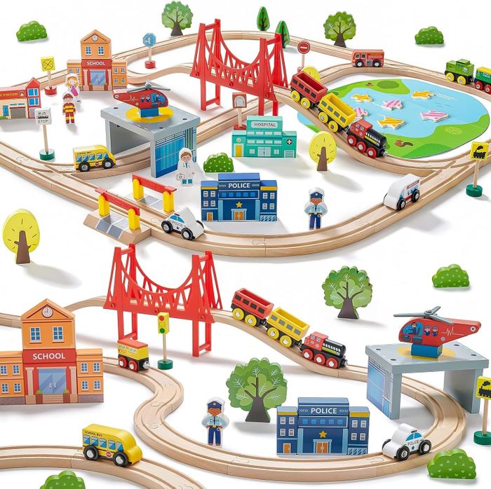 A wooden train set with tracks, bridges, and buildings like a school and police station, complete with toy cars and figures arranged in a playful scene.