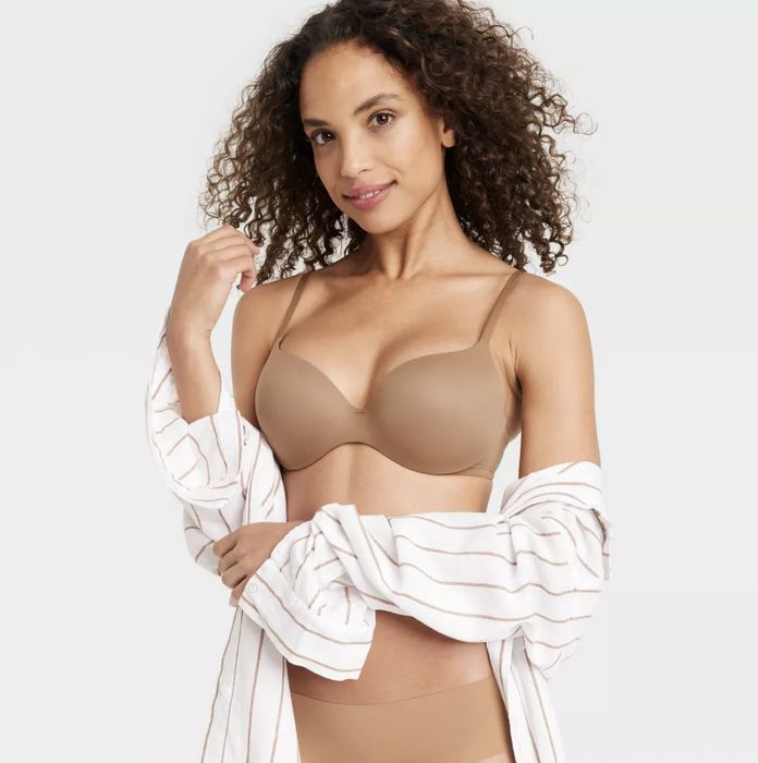 A model wearing a strapless bra while holding an open white striped shirt