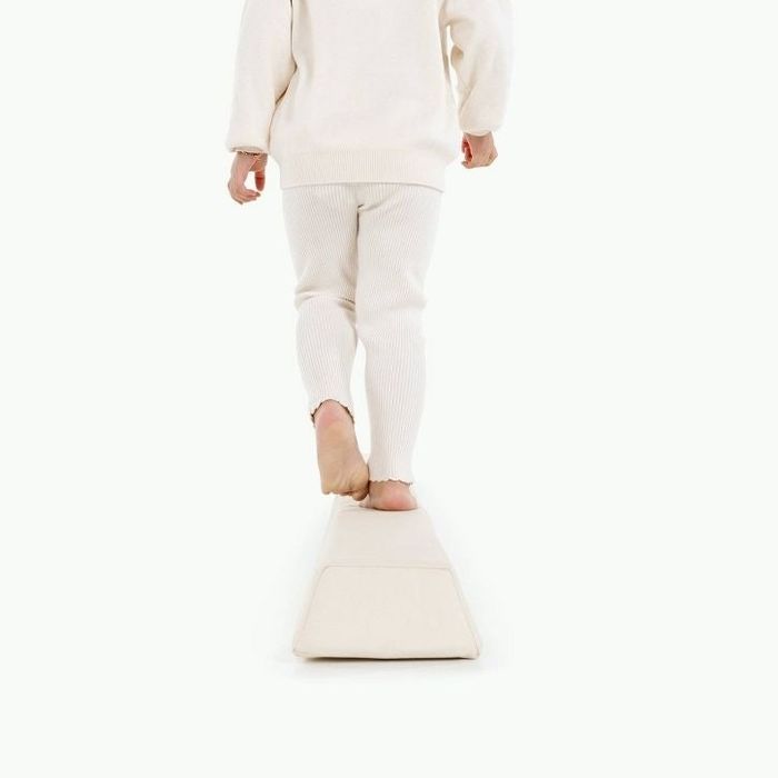 A person dressed in cozy knitwear walks along a soft balance beam, showcased in a shopping article