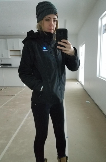 A reviewer showcasing a black hooded jacket
