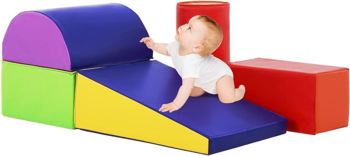 A baby crawling over colorful, soft play blocks.
