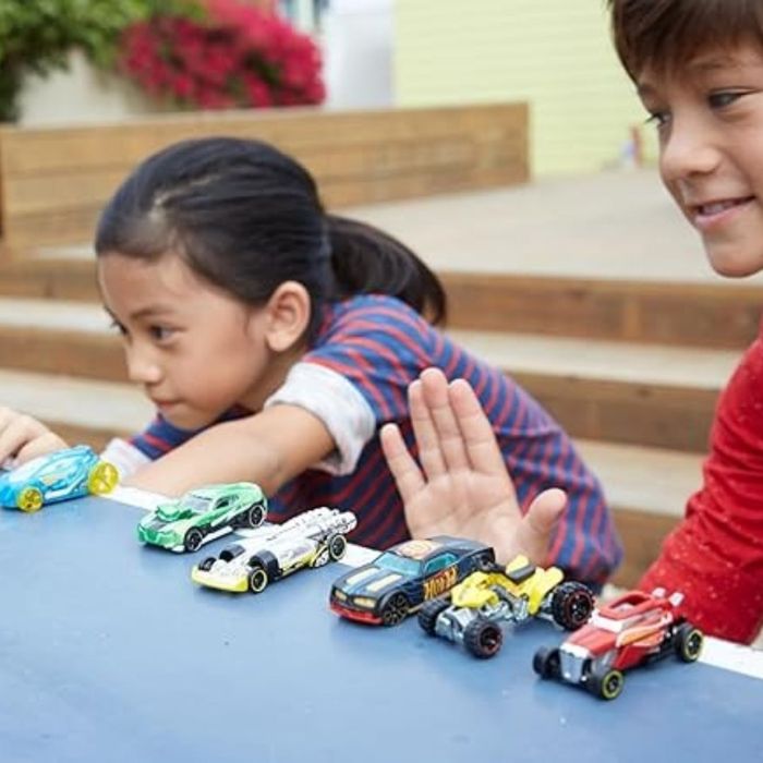 Two children having fun outdoors, arranging toy cars in a neat line on the steps. The scene captures the energy and joy of playtime as they immerse themselves in their car collection.