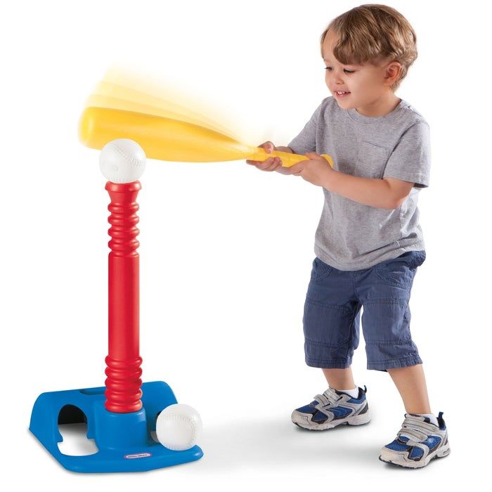 A child having fun with a toy baseball set, gripping a plastic bat and hitting a ball off the tee