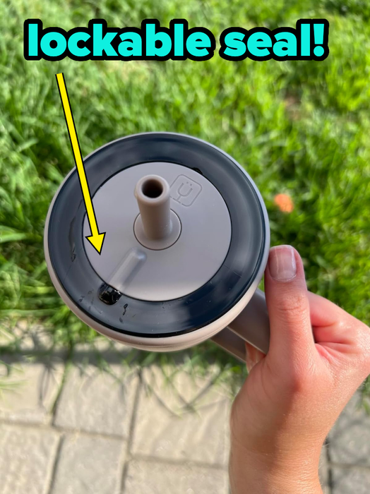 a person holding a cup featuring a lockable seal lid and straw, with text emphasizing the spill-proof design