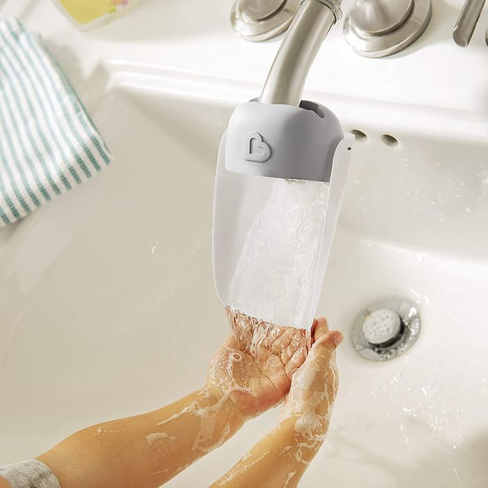 a child using a faucet extender to wash their hands independently