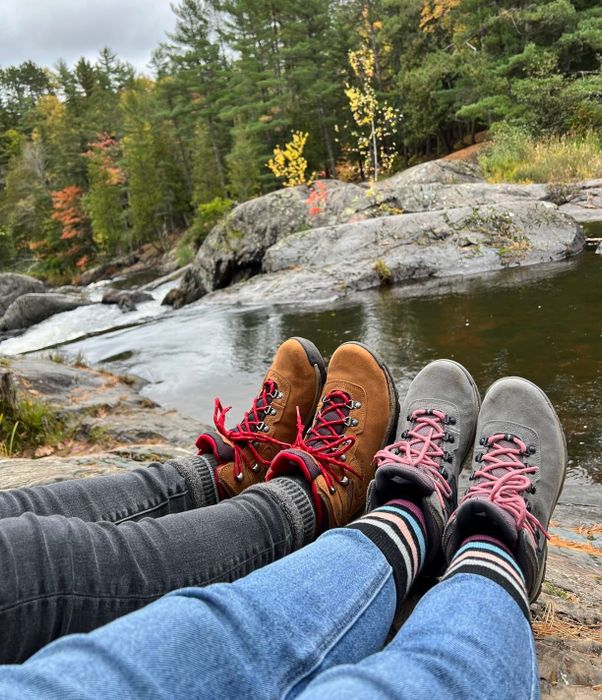 Reviewer photo showing two pairs of hiking boots: one in brown with red laces and another in gray with pink laces.