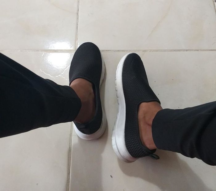 Reviewer wearing black slip-on sneakers with white soles.