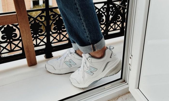 Reviewer standing on a balcony, wearing white sneakers with rolled-up jeans.