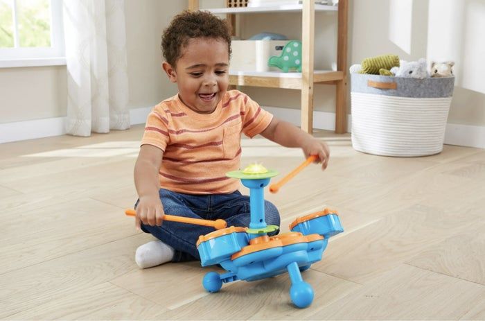 Child enjoying playtime with a toy drum set indoors