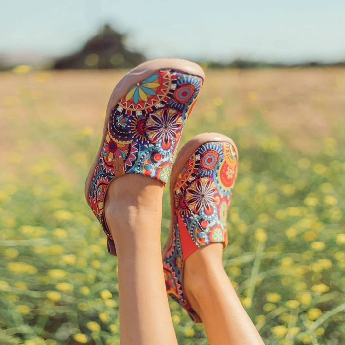 A model shows off colorful UIN slip-on shoes, showcasing intricate, artistic patterns.