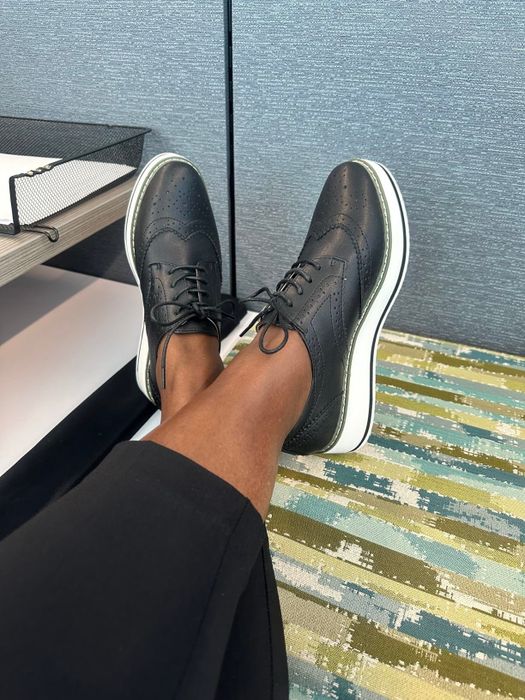 A close-up of a reviewer rocking the wingtip shoes in black leather with contrasting white soles.