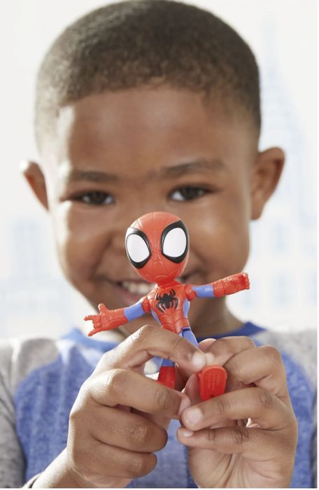 A child is happily holding a Spider-Man action figure, smiling at the camera.