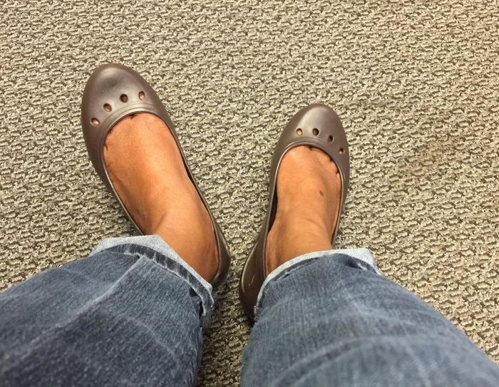Reviewer wearing brown Crocs ballet flats with four oval cut-outs on the toe box, paired with blue jeans.