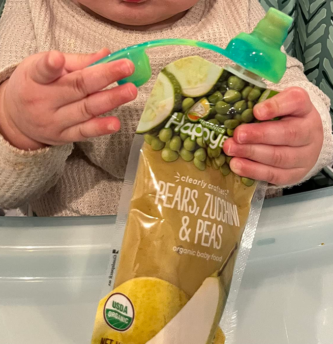 photo of a child holding a food pouch with a green silicone lid securely attached