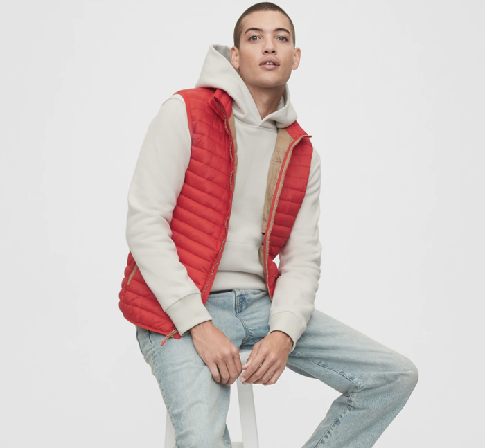 Model wearing a puffer vest in a bold vermillion shade.