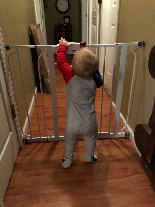 photo of a child attempting to open the baby gate, showcasing its child-resistant design