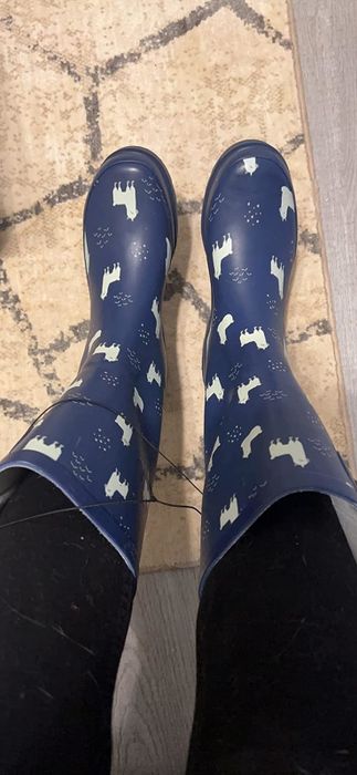 Reviewer sporting knee-high rain boots decorated with white llamas.