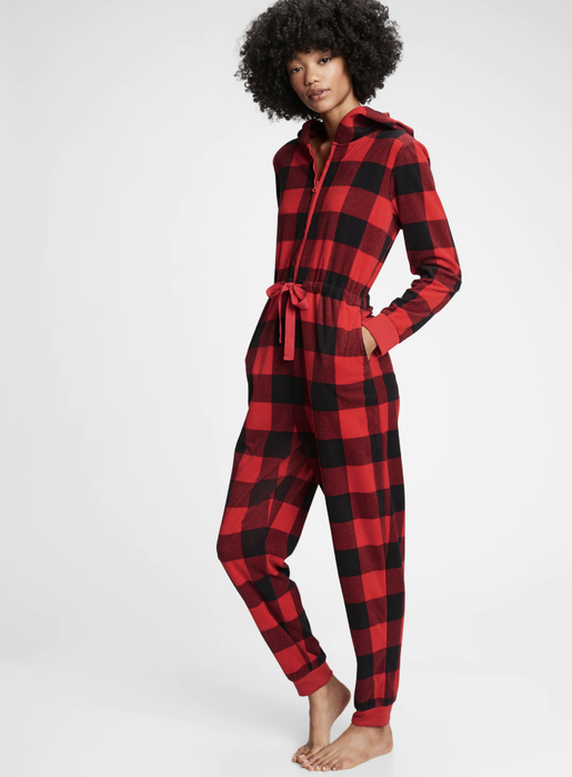 Model wearing onesie pajamas featuring a red buffalo plaid print