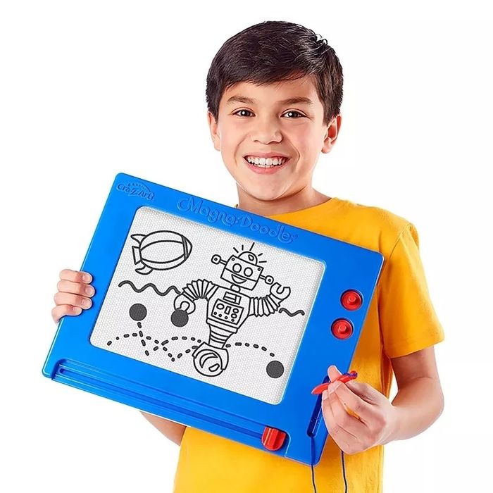 A young child holds a Magna Doodle with a drawing of a robot and a blimp.