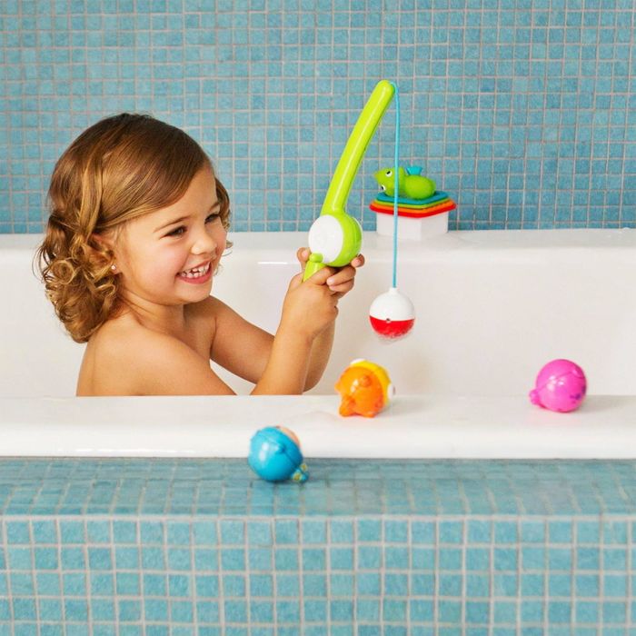A child playing with a fishing toy set in the bathtub, smiling as colorful bath toys float around them